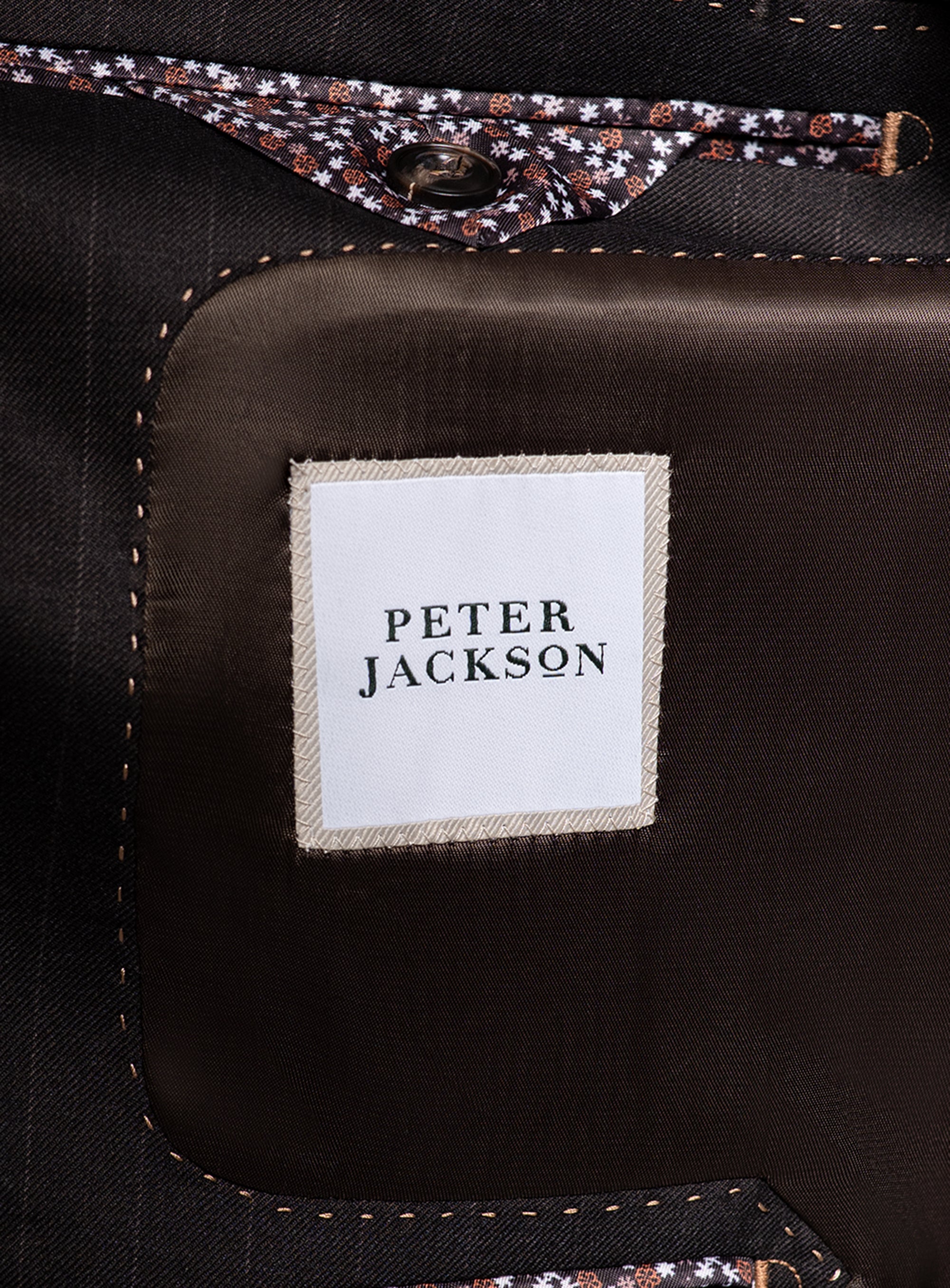 Close-up of a 'Peter Jackson' label on a dark fabric background