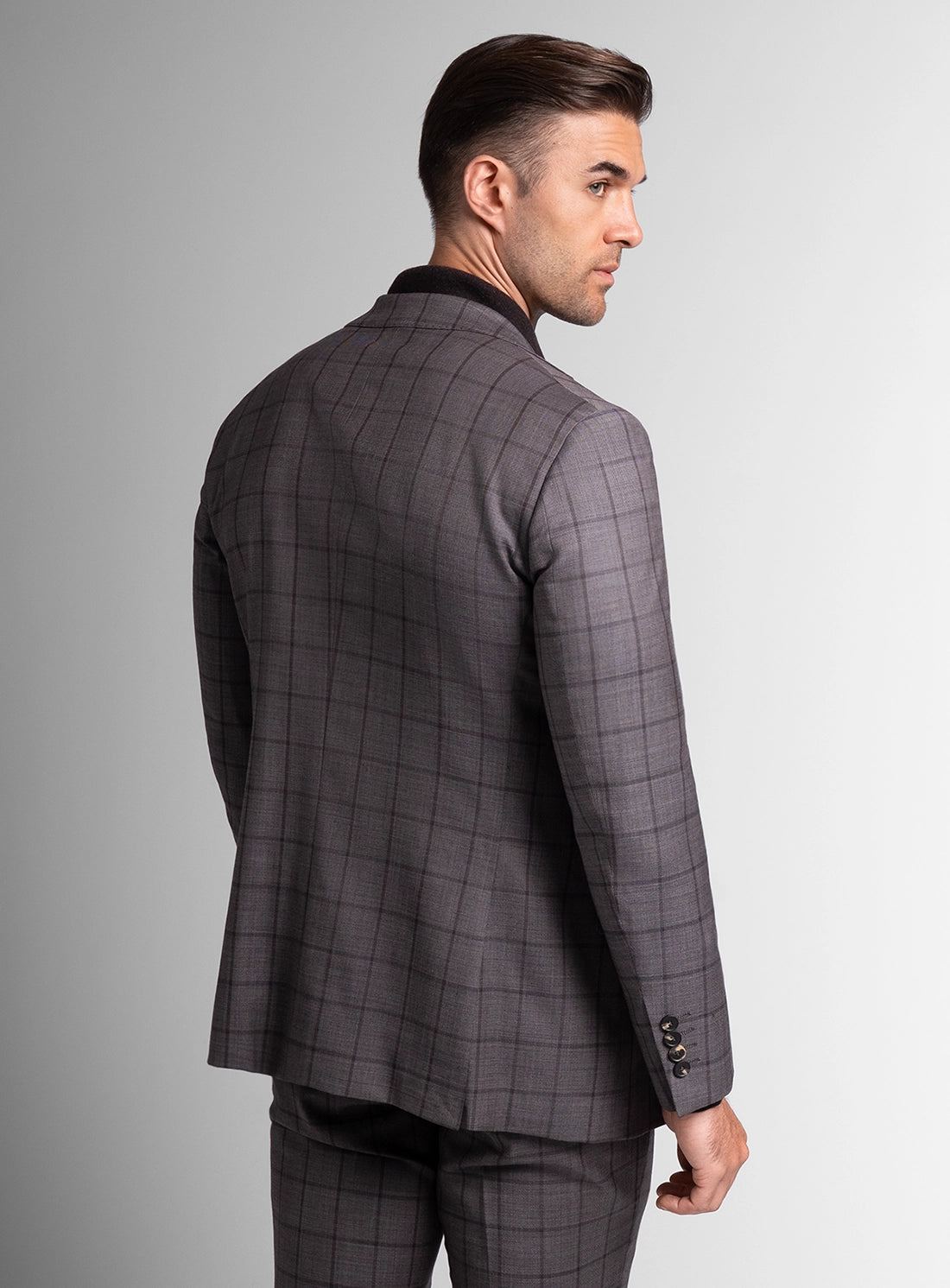Man wearing a gray checkered suit jacket on a gray background