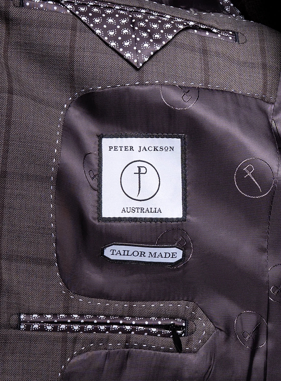Close-up of a suit label with 'Peter Jackson Australia' branding on a gray fabric background.