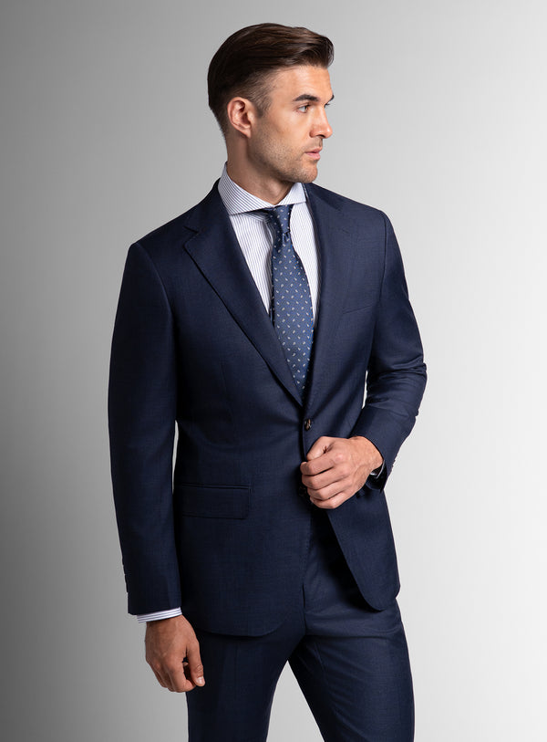 Man wearing a navy suit with a light gray background