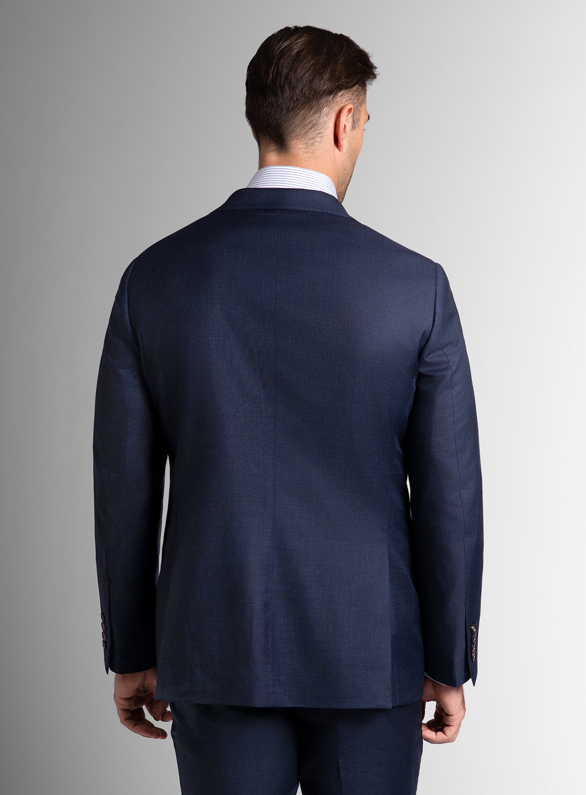 Man wearing a navy blue suit jacket on a gray background