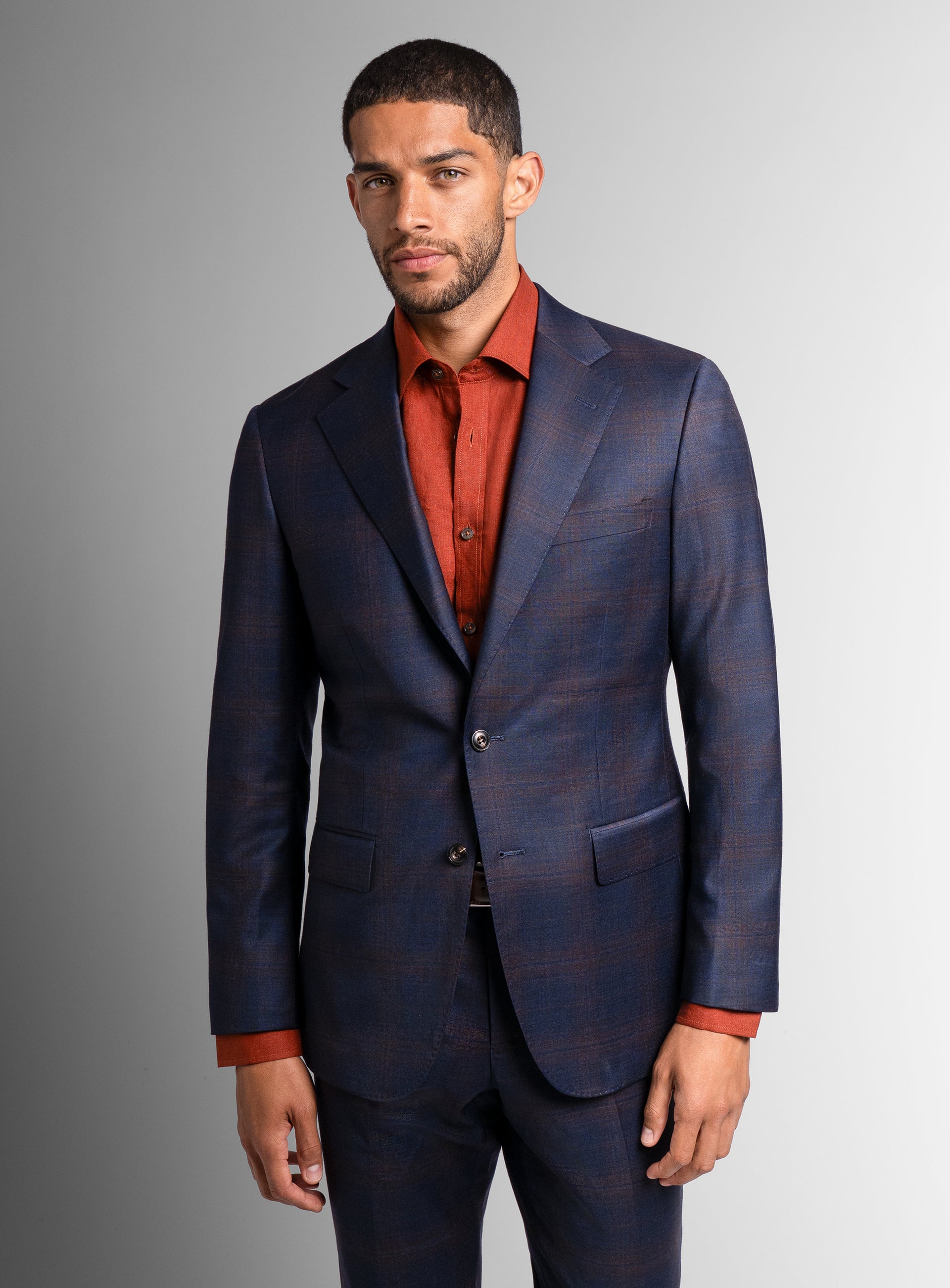 Close-up of a man wearing the Fredo Bronze Plaid Navy Suit with an orange shirt