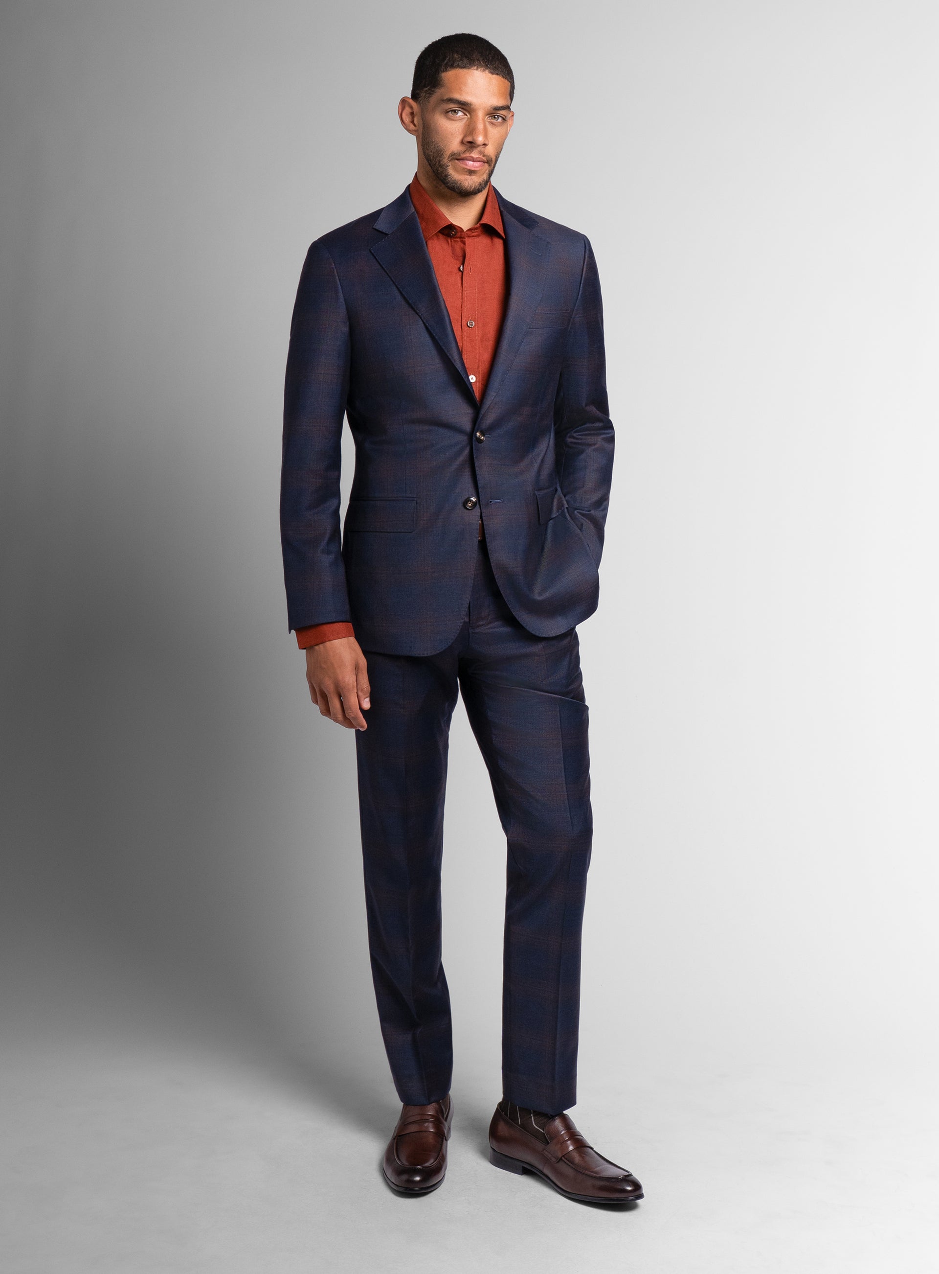 A man wearing the Fredo Bronze Plaid Navy with an orange shirt