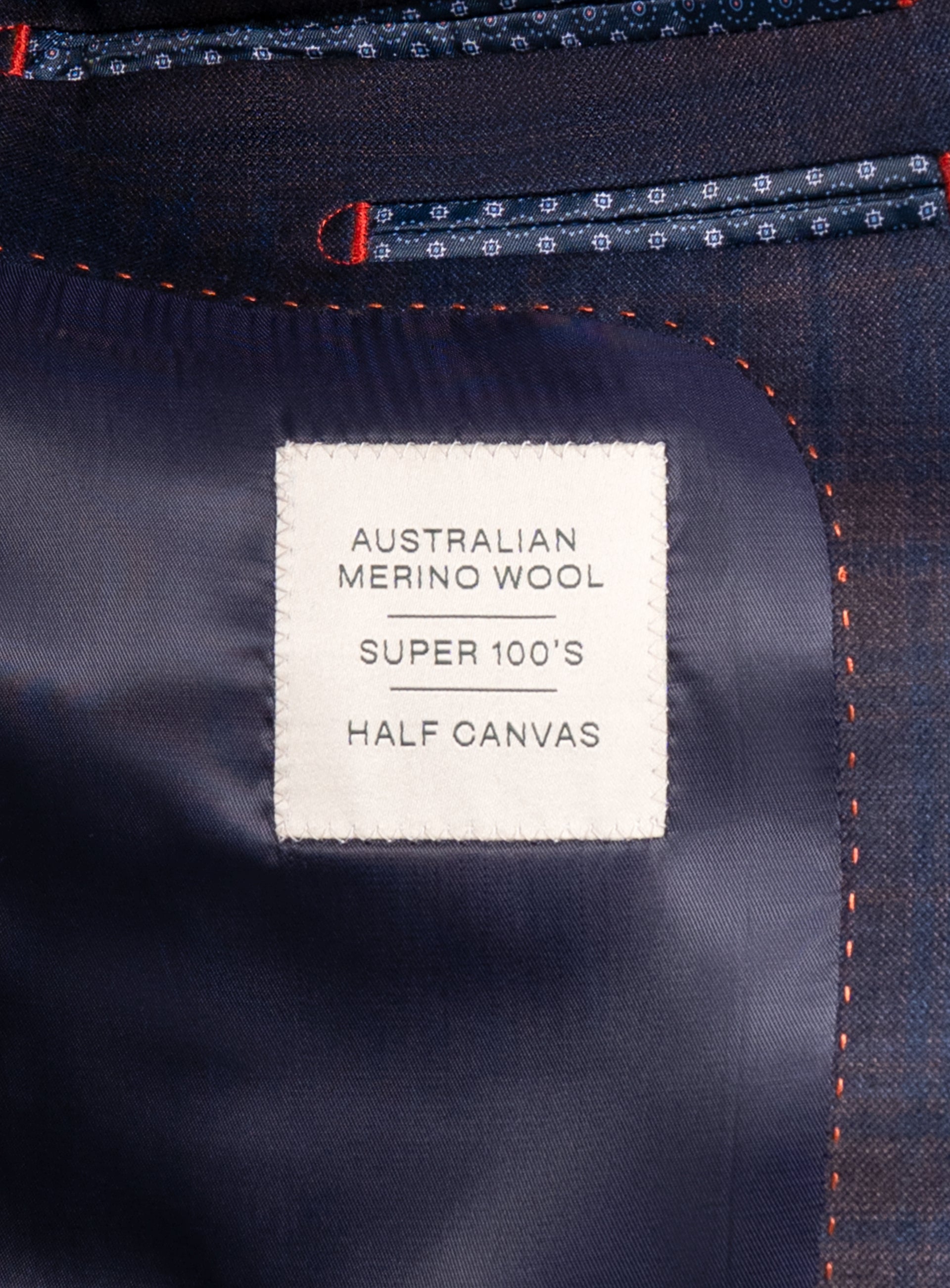 Picture of a label that says "Australian Merino Wool - Super 100's - Half Canvas" on the Fredo Bronze Plaid Navy Suit