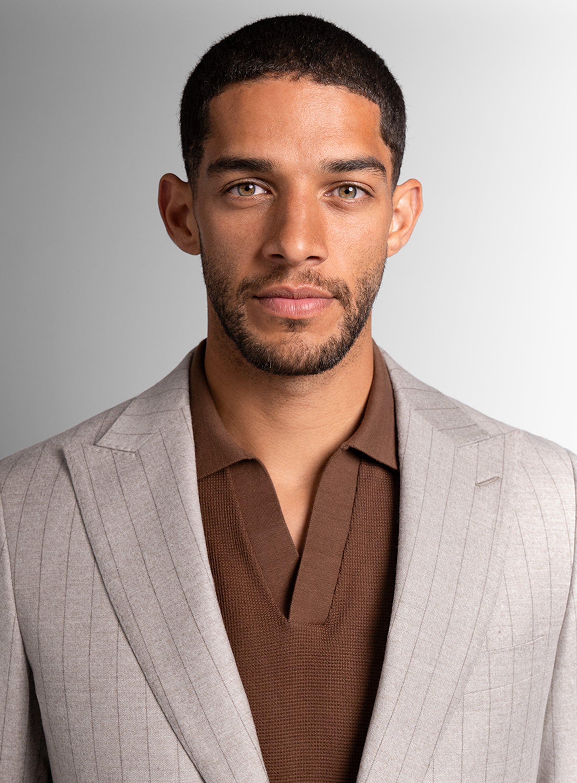 Close up of man wearing white suit and brown shirt