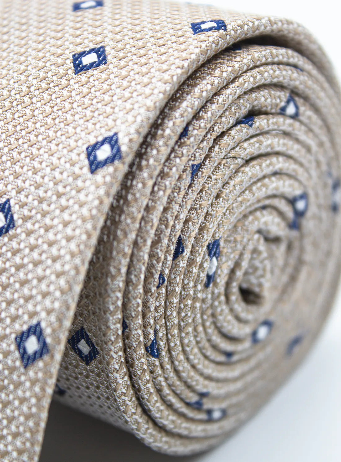 Roll of beige fabric with blue diamond patterns on a white background