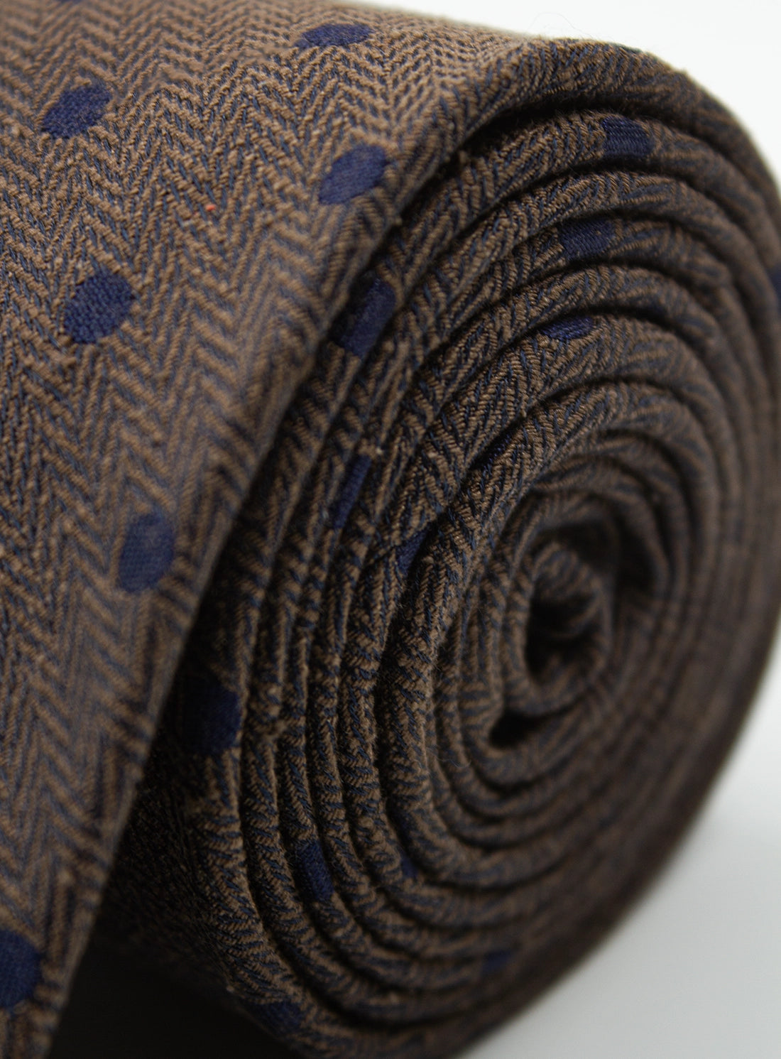 Close-up of a brown fabric roll with blue pattern on a white background