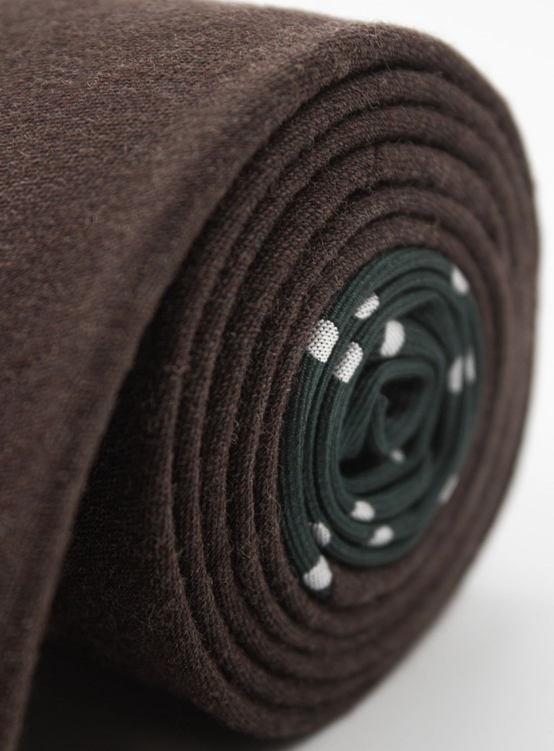 Roll of brown fabric with a green and white patterned core on a white background