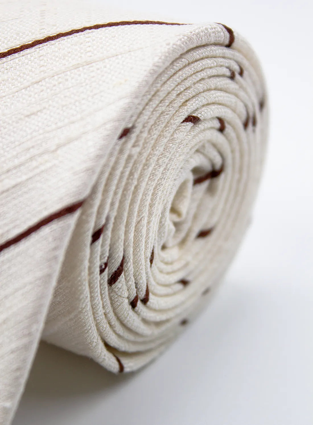 Rolled-up white fabric with brown stripes on a light gray background