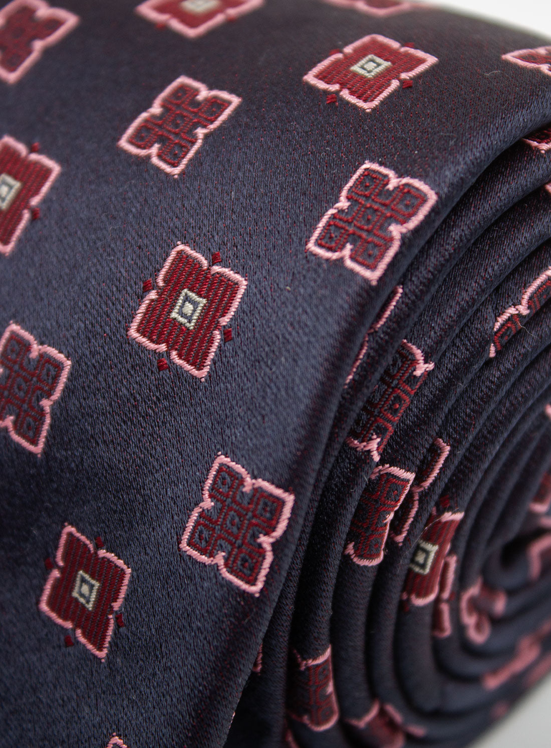 Close up of the Bottinelli Nero Rosso Geo Navy Silk Tie rolled up