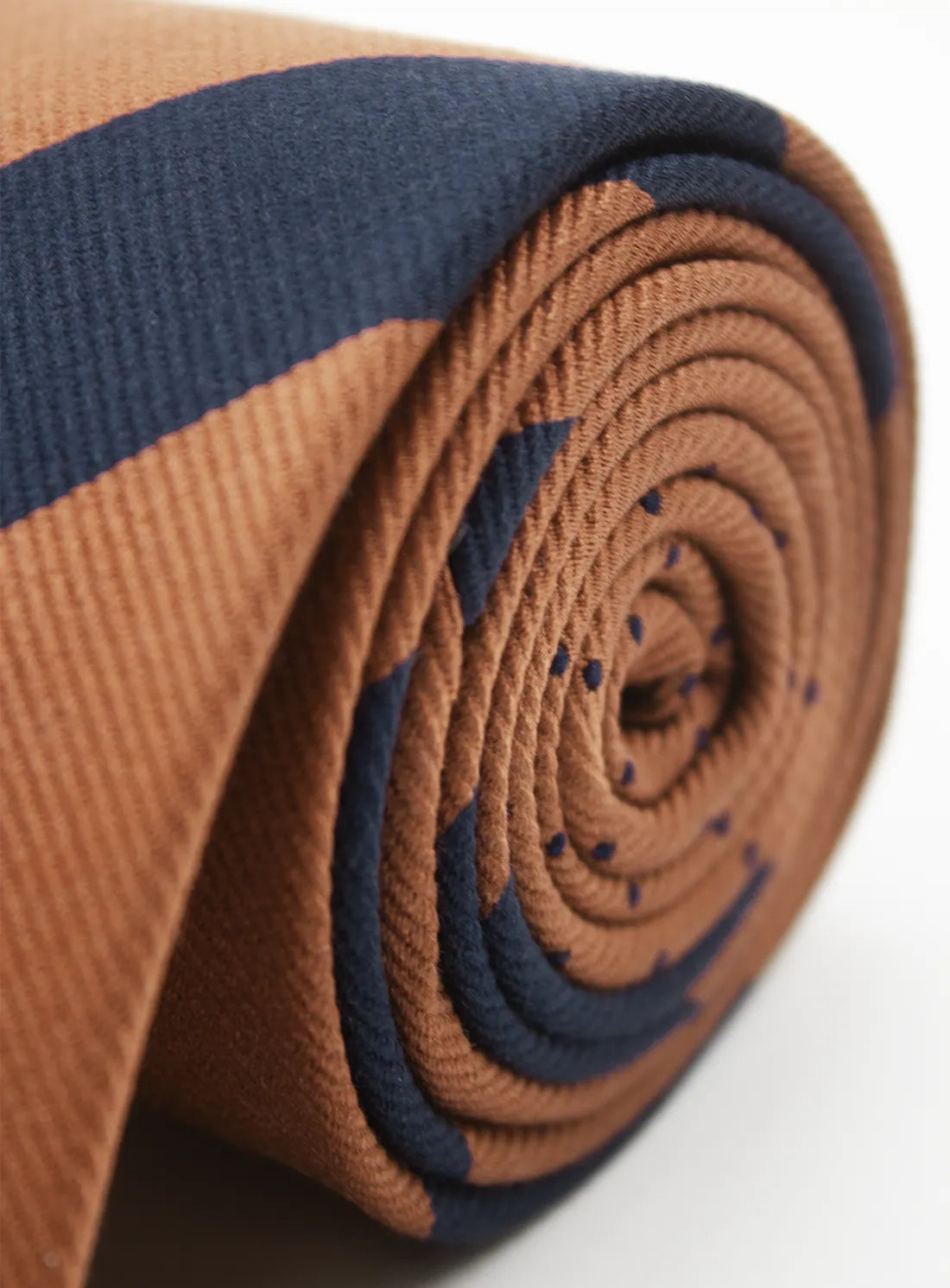 Rolled-up brown and navy yoga mat on a white background