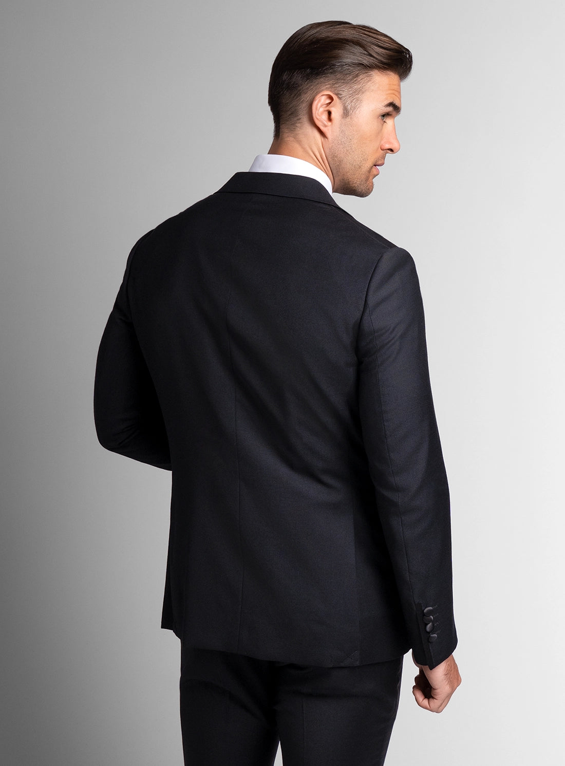 Man wearing a black suit jacket on a gray background