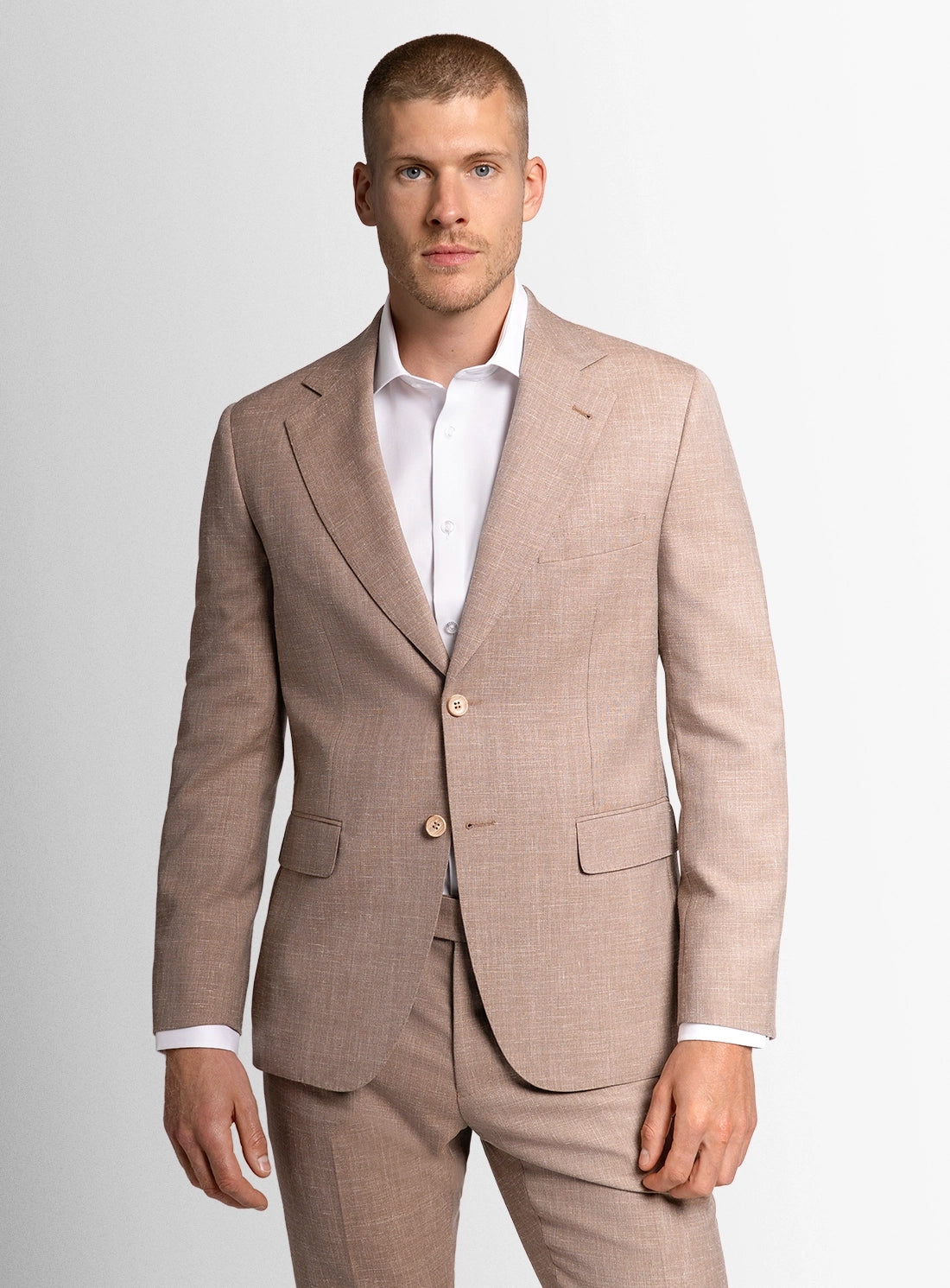Man wearing a beige suit with a white shirt on a light gray background