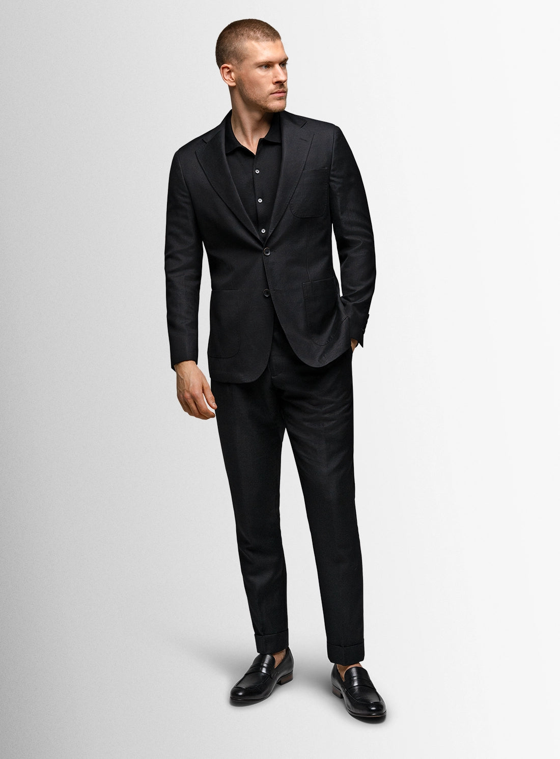 Man wearing a black suit on a light gray background