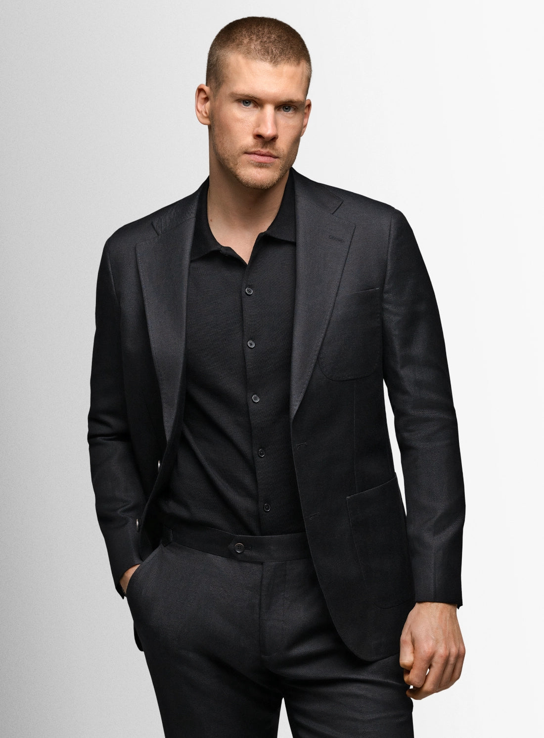 Man wearing a black suit against a gray background