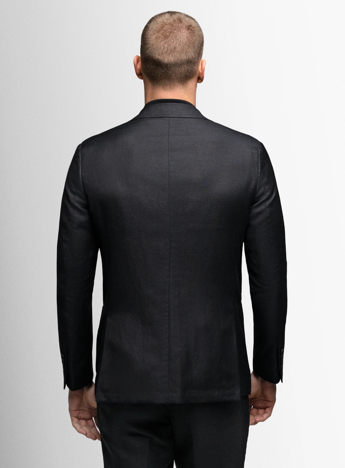 Man wearing a black suit jacket on a plain background