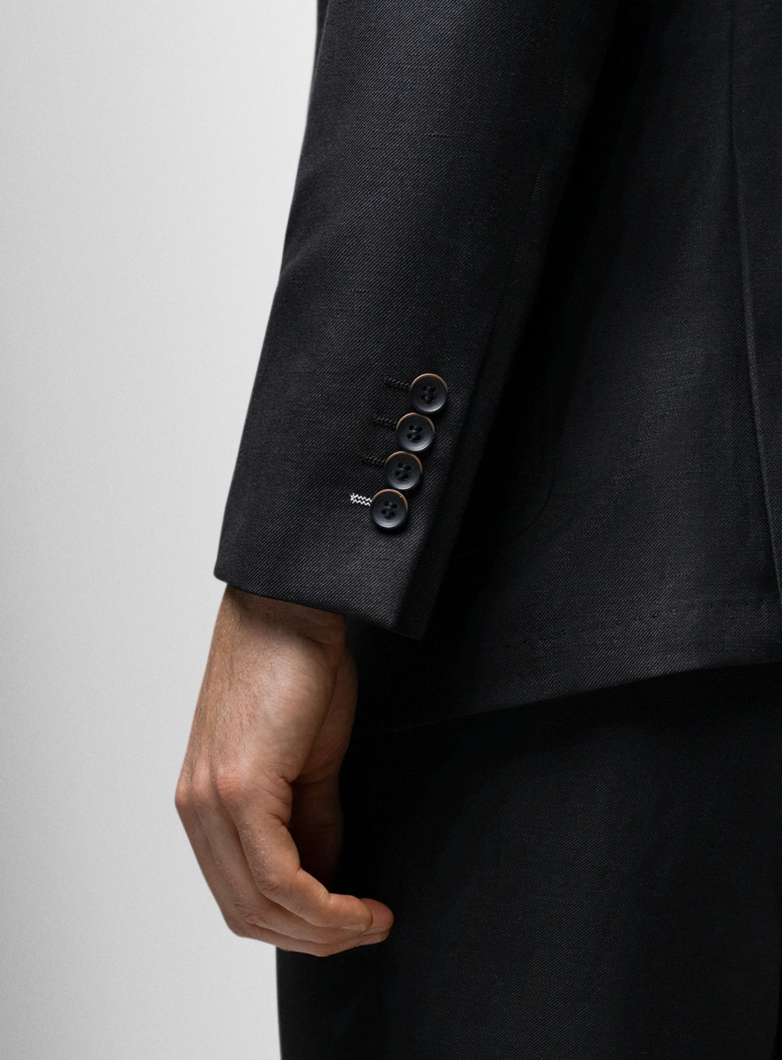 Close-up of a black suit jacket with buttons on a light gray background