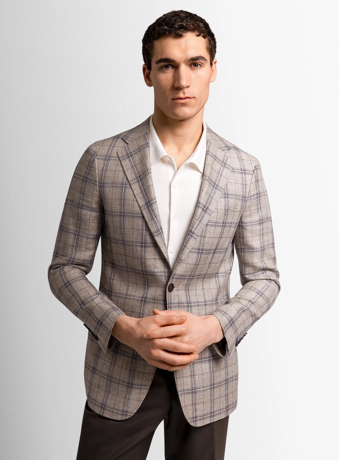 Man wearing a plaid blazer over a white shirt on a light gray background