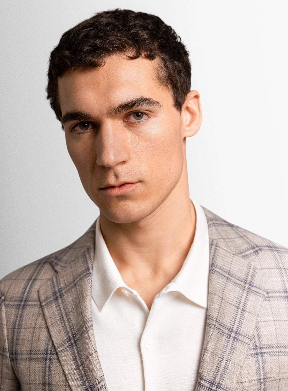 Man wearing a checkered blazer over a white shirt against a plain background