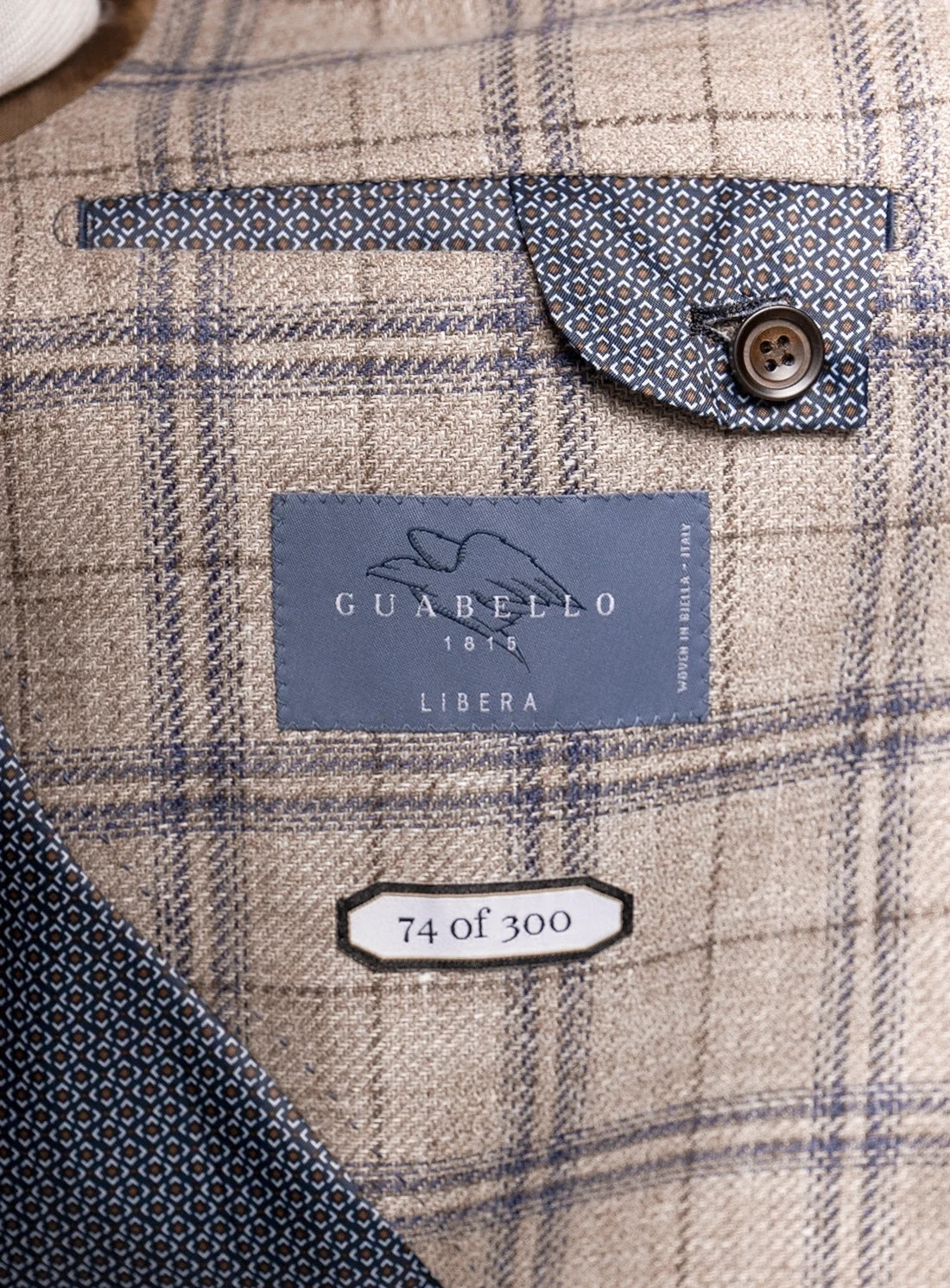 Close-up of a plaid fabric with a Guabello label and button detail.