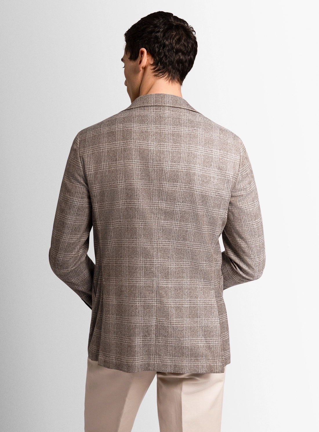 Man wearing a patterned blazer and beige pants on a plain background