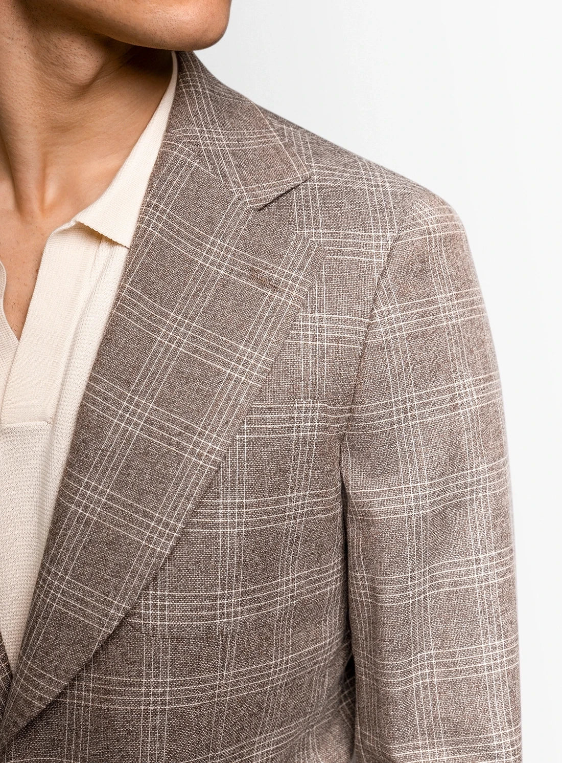 Brown checkered blazer worn by a person on a light gray background
