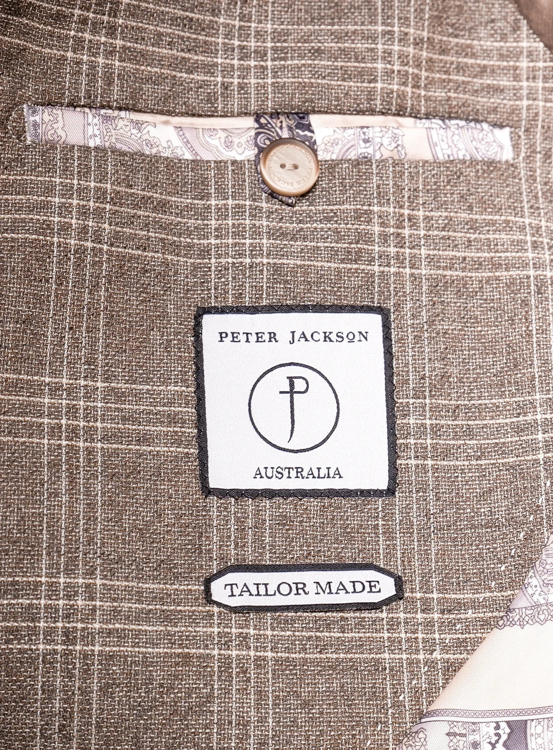 Close-up of a 'Peter Jackson Australia' tailor-made label on a textured fabric background.