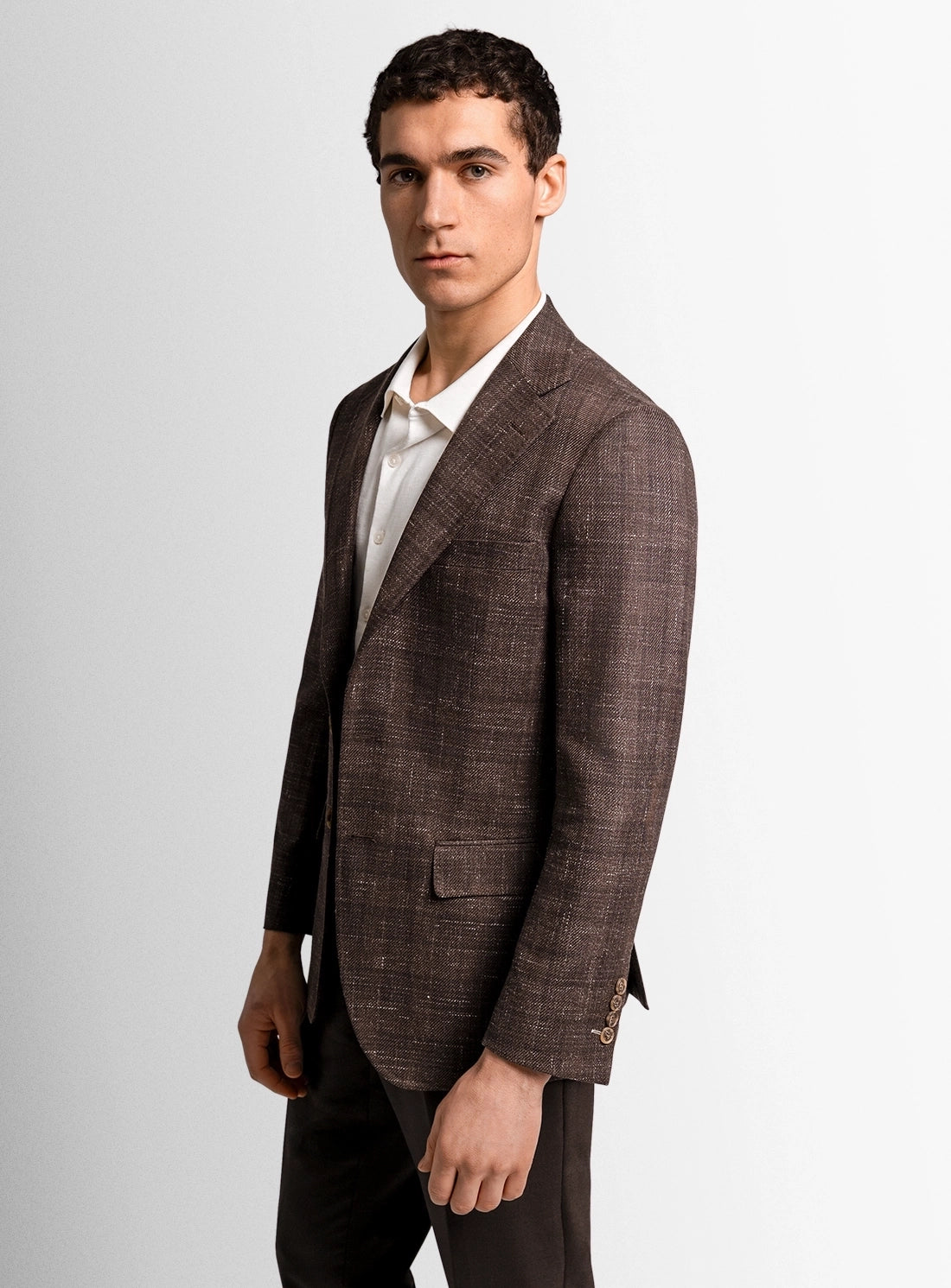 Man wearing a brown checkered suit jacket on a light gray background