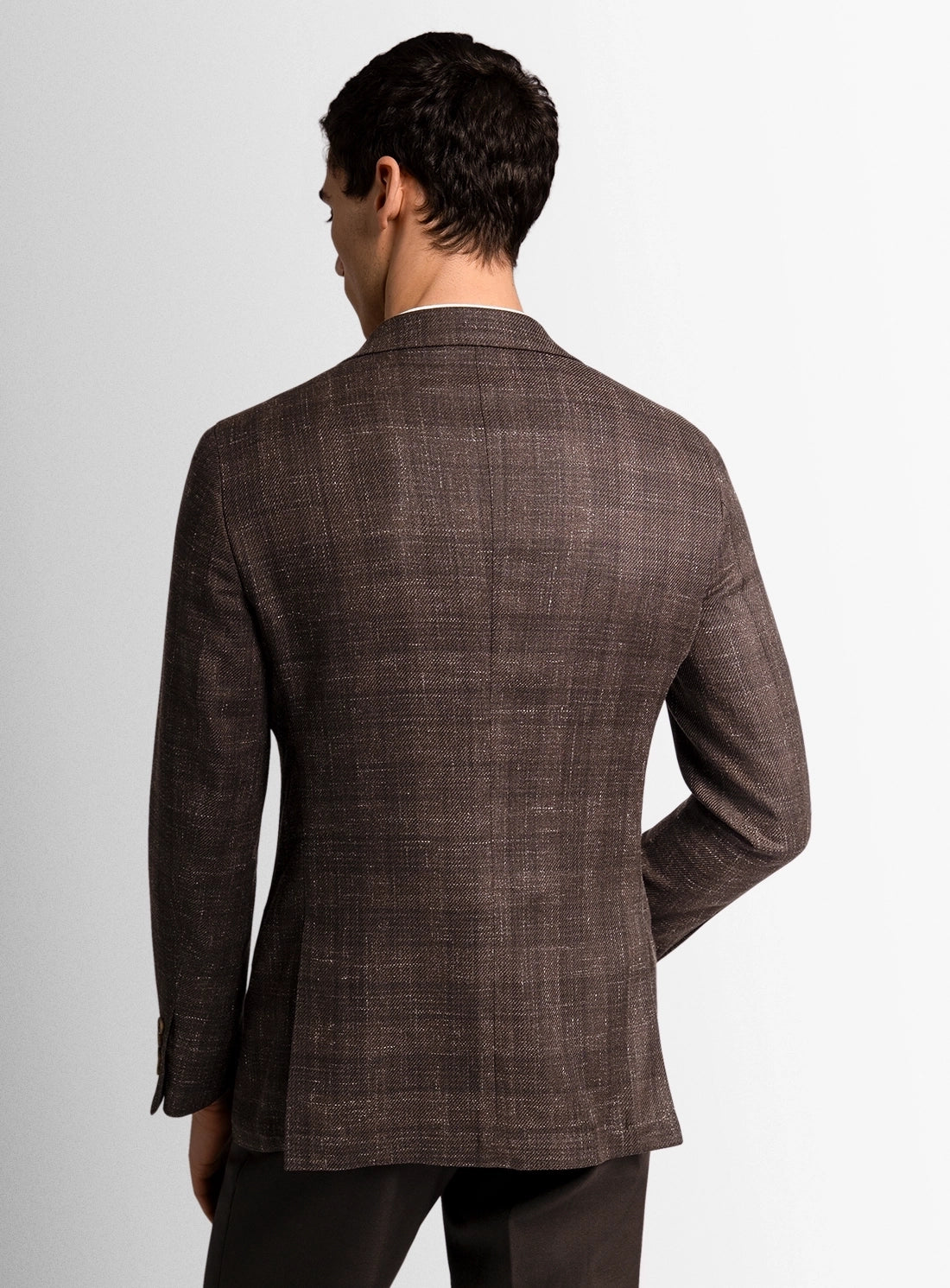 Man wearing a brown checkered blazer on a white background