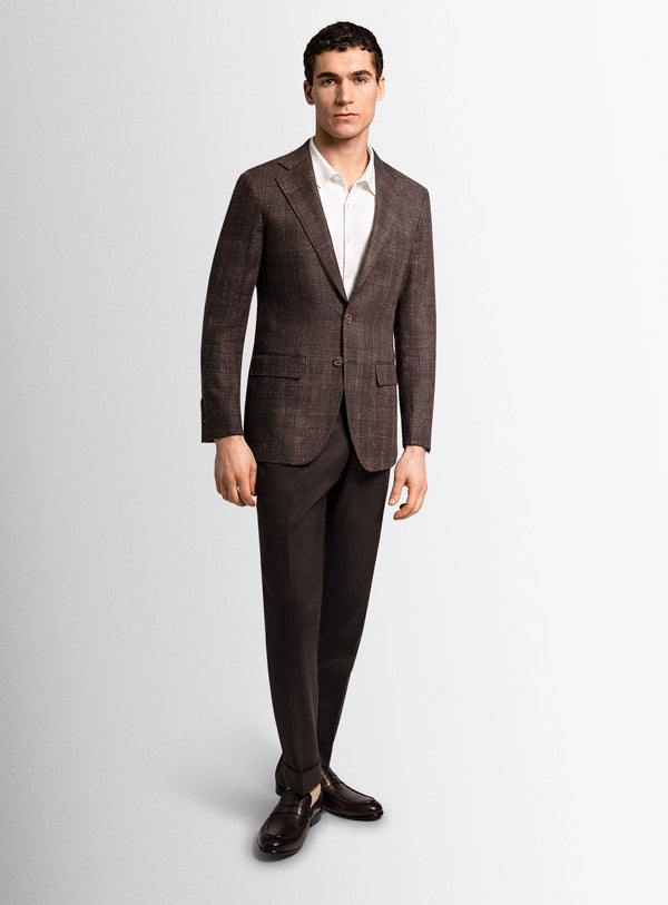 Man wearing a brown checkered suit on a light gray background