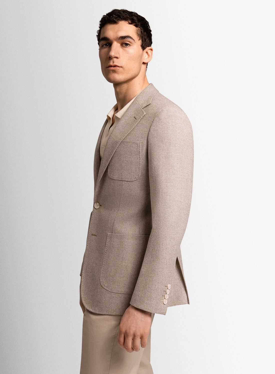 Man wearing a beige suit jacket on a light gray background
