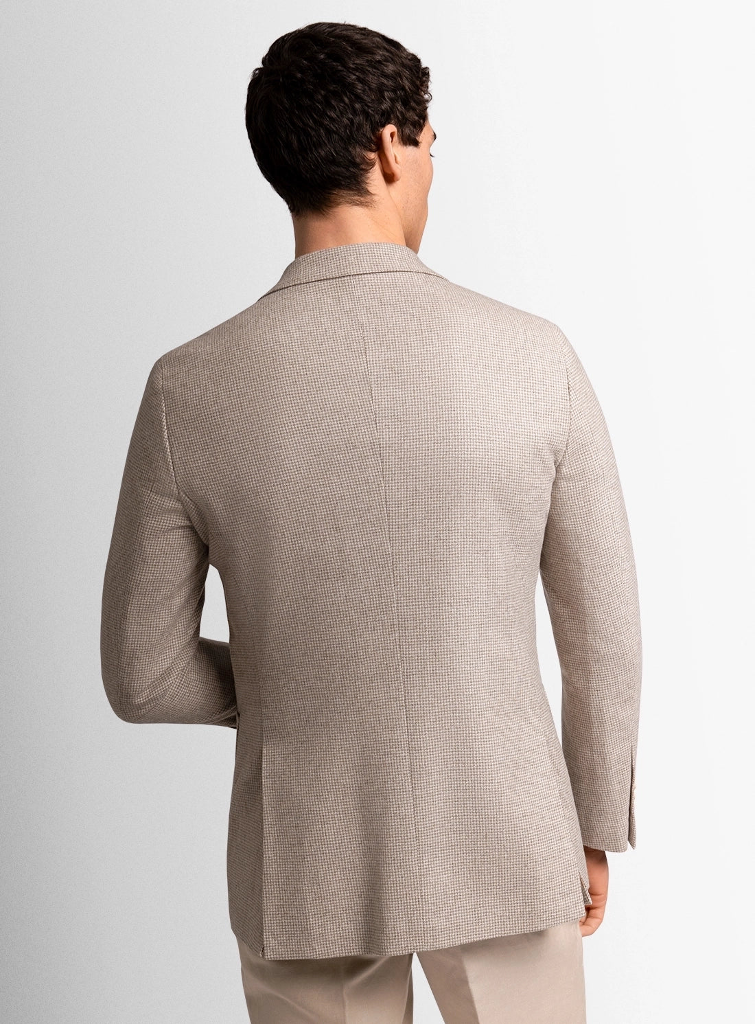 Man wearing a beige suit jacket on a light gray background
