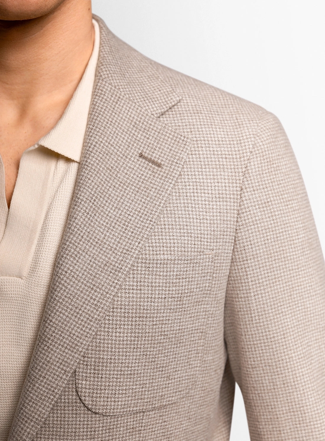 Close-up of a beige checkered blazer on a plain background