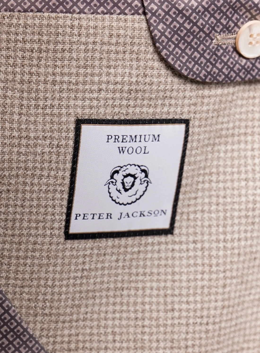 Close-up of a 'Premium Wool' label on a textured fabric surface with a button partially visible.