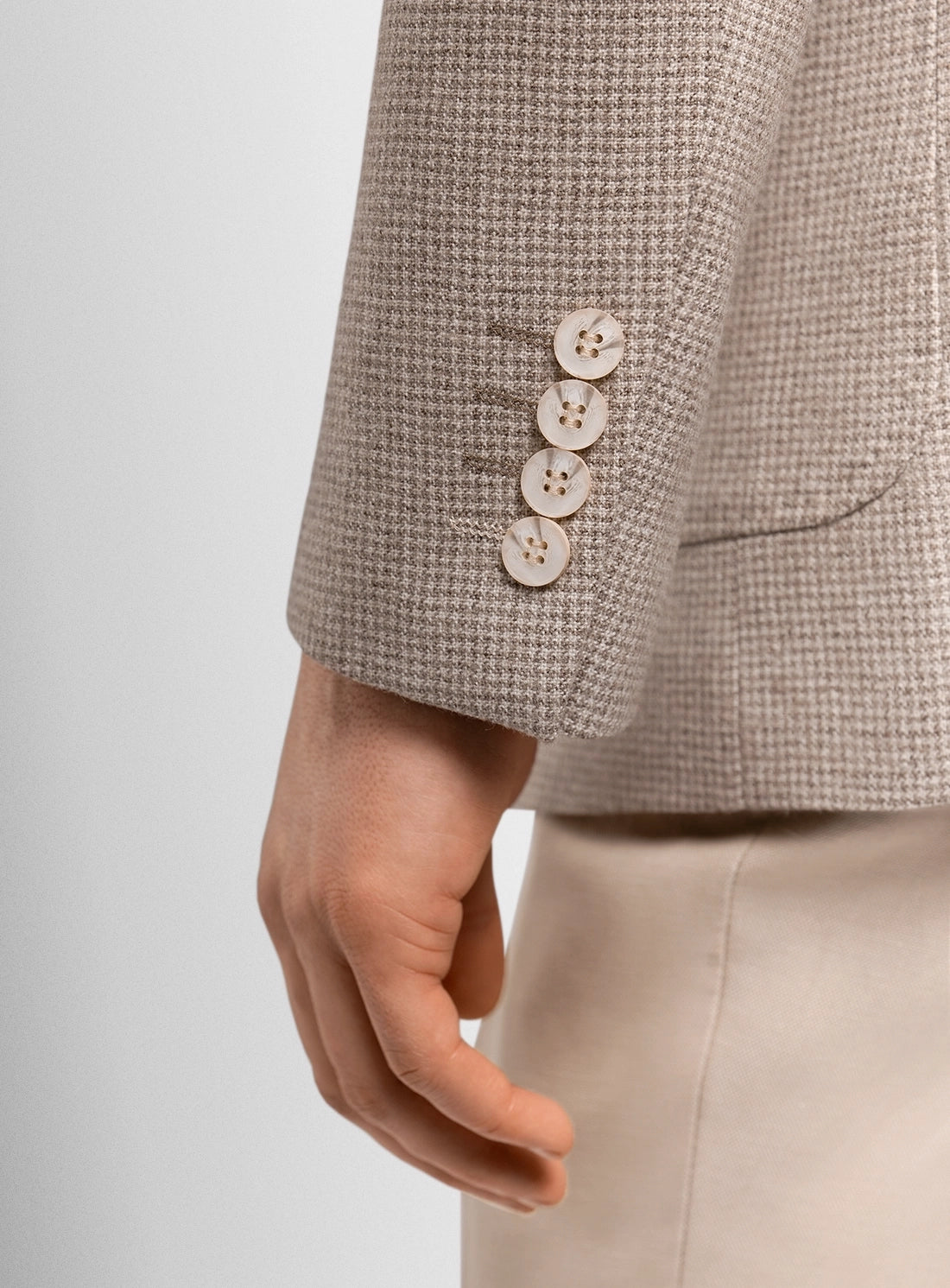 Close-up of a textured jacket with buttons on a plain background