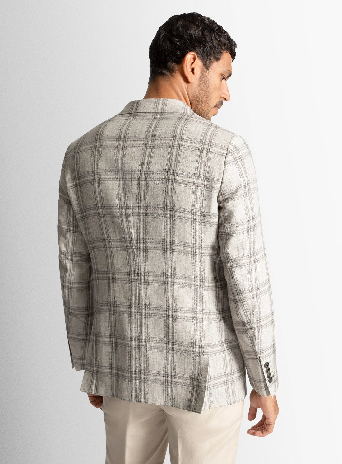 Man wearing a gray plaid blazer on a light gray background