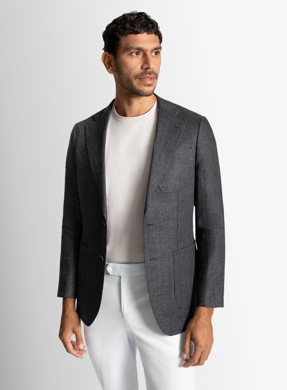 Man wearing a gray blazer over a white shirt and pants on a light gray background