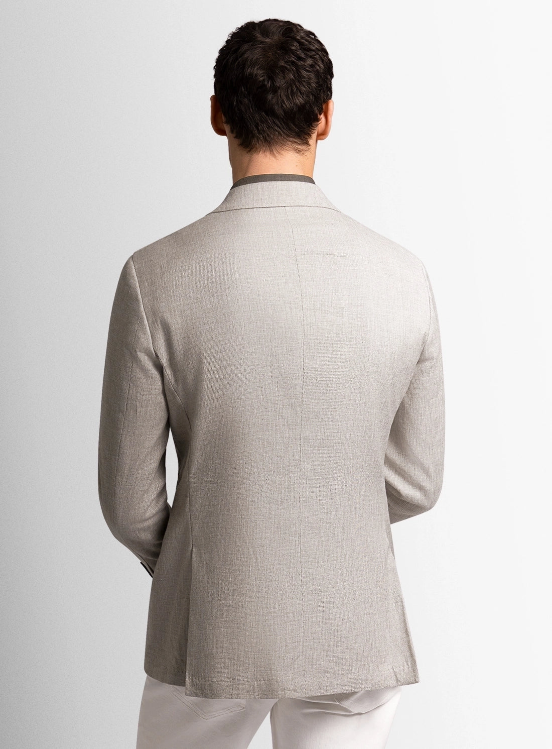 Man wearing a light gray blazer on a plain background