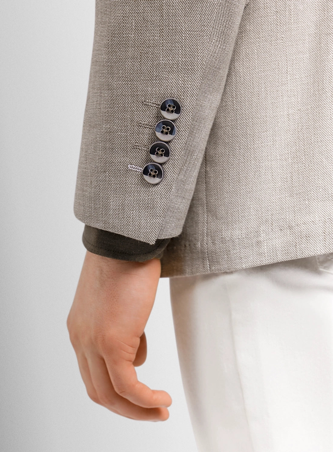 Close-up of a gray textured blazer with three buttons on a light gray background