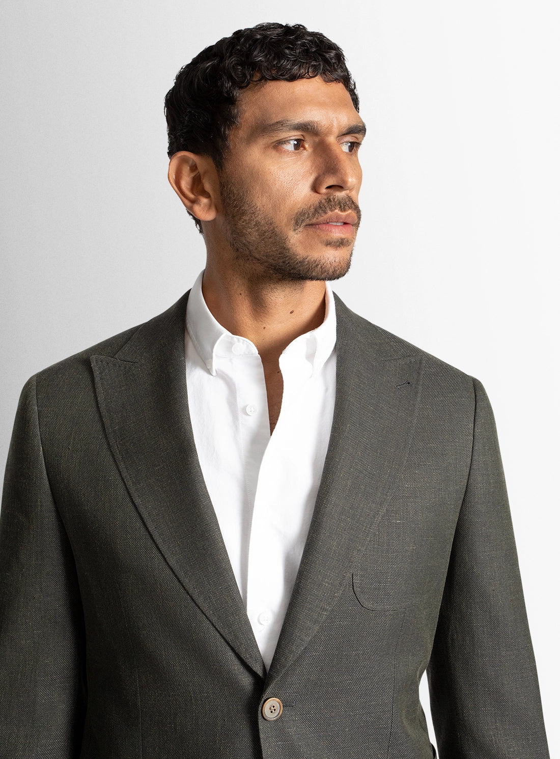 Man wearing a gray suit jacket over a white shirt on a light gray background