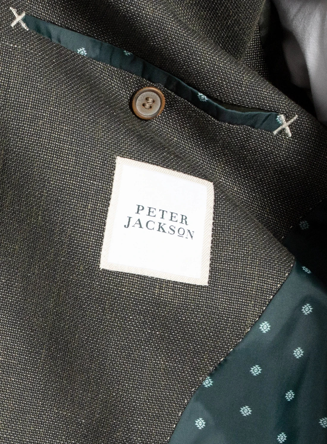 Close-up of a 'Peter Jackson' label on a garment with a dark fabric background.