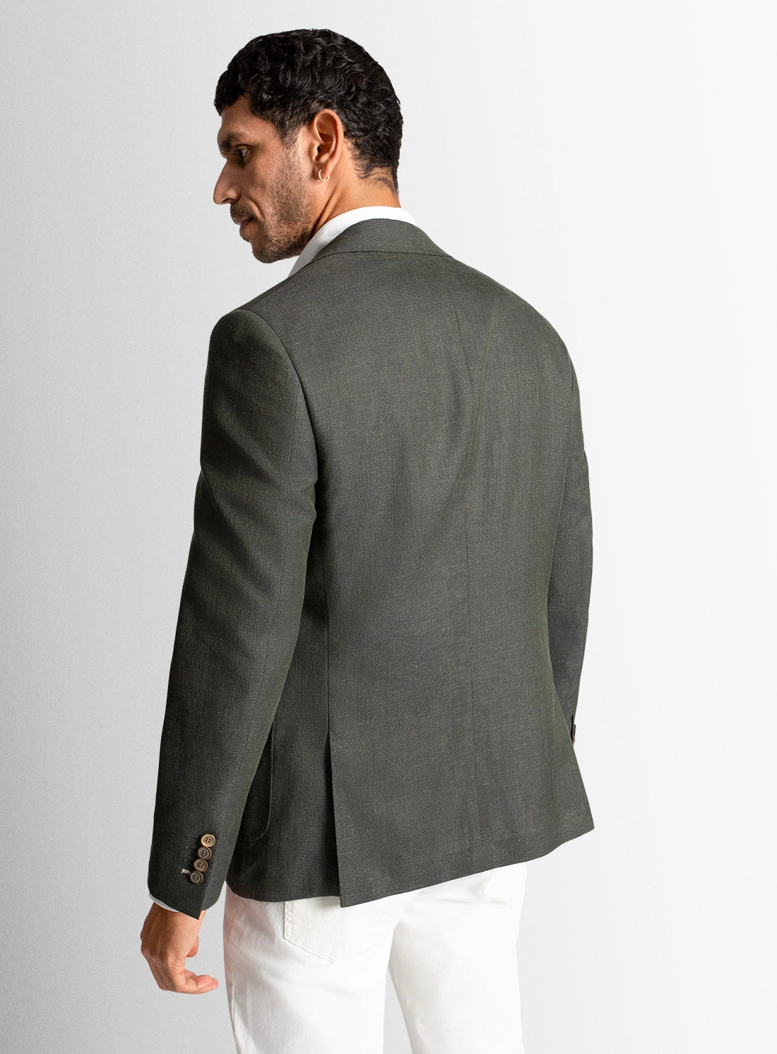 Man wearing a gray blazer and white pants on a light gray background