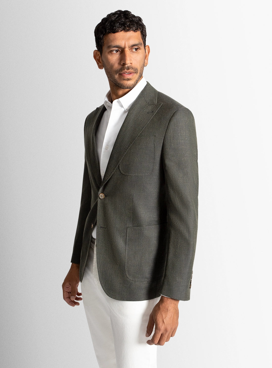 Man wearing a gray blazer over a white shirt on a light gray background