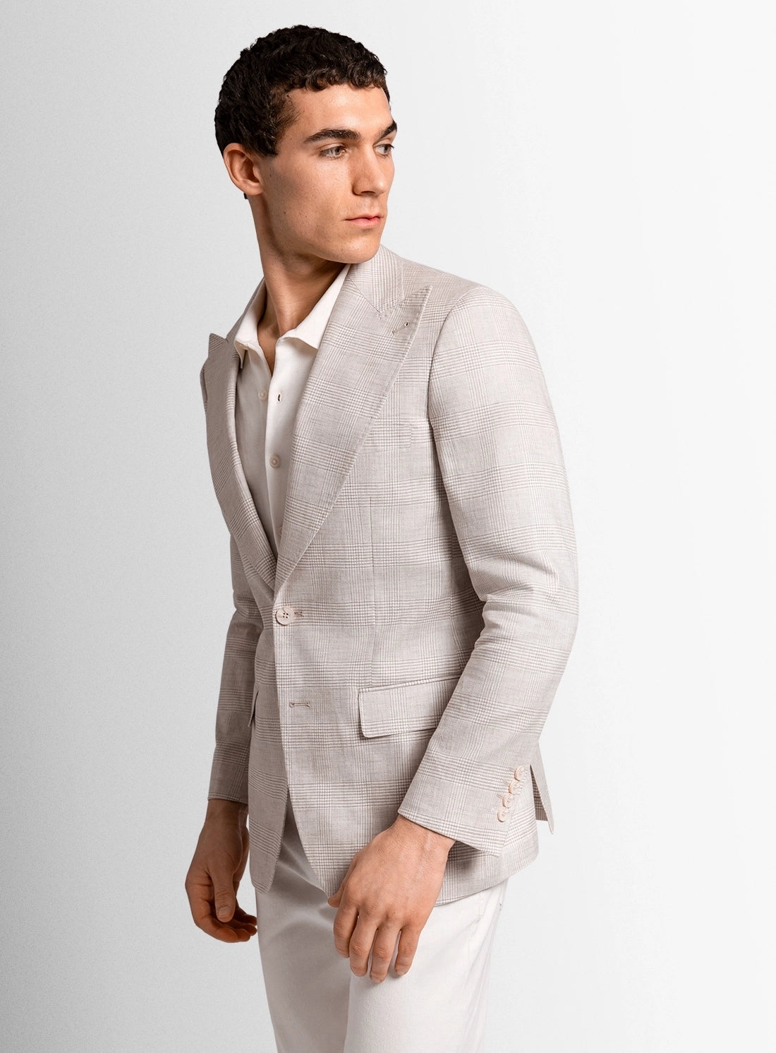 Man wearing a light gray suit jacket over a white shirt on a plain background
