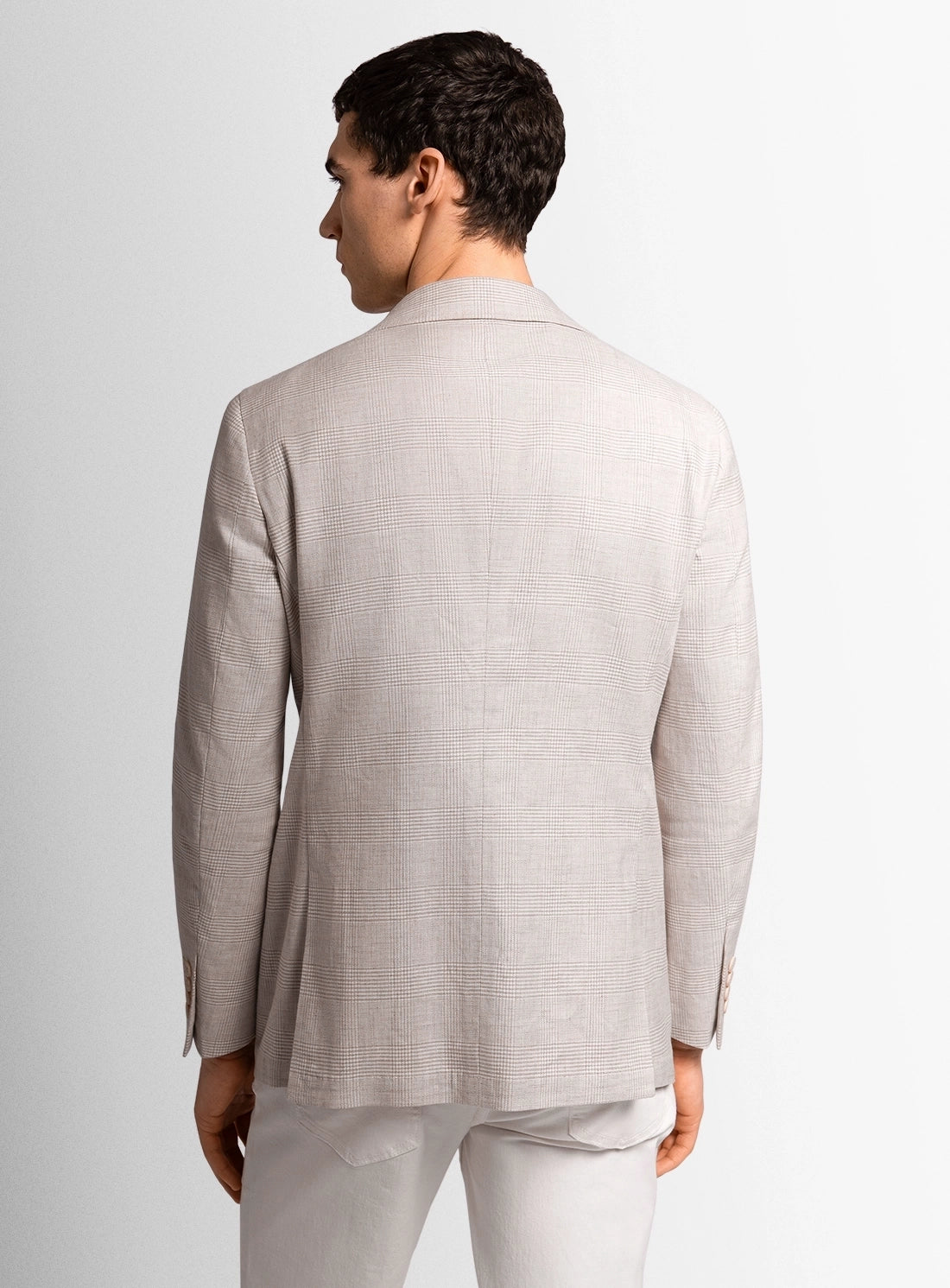 Man wearing a light gray suit jacket and pants on a white background