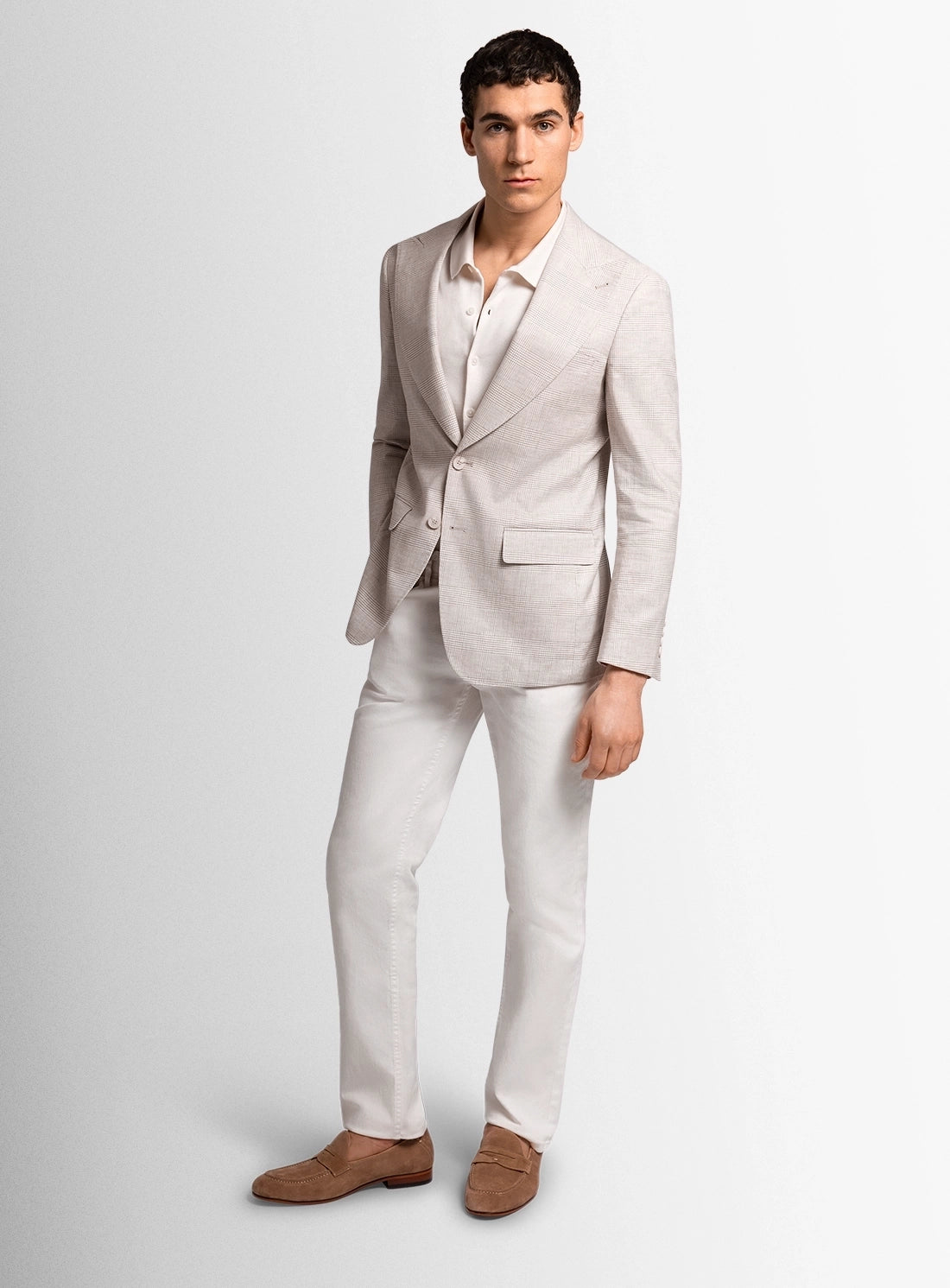 Man wearing a light gray suit with a white shirt on a plain background