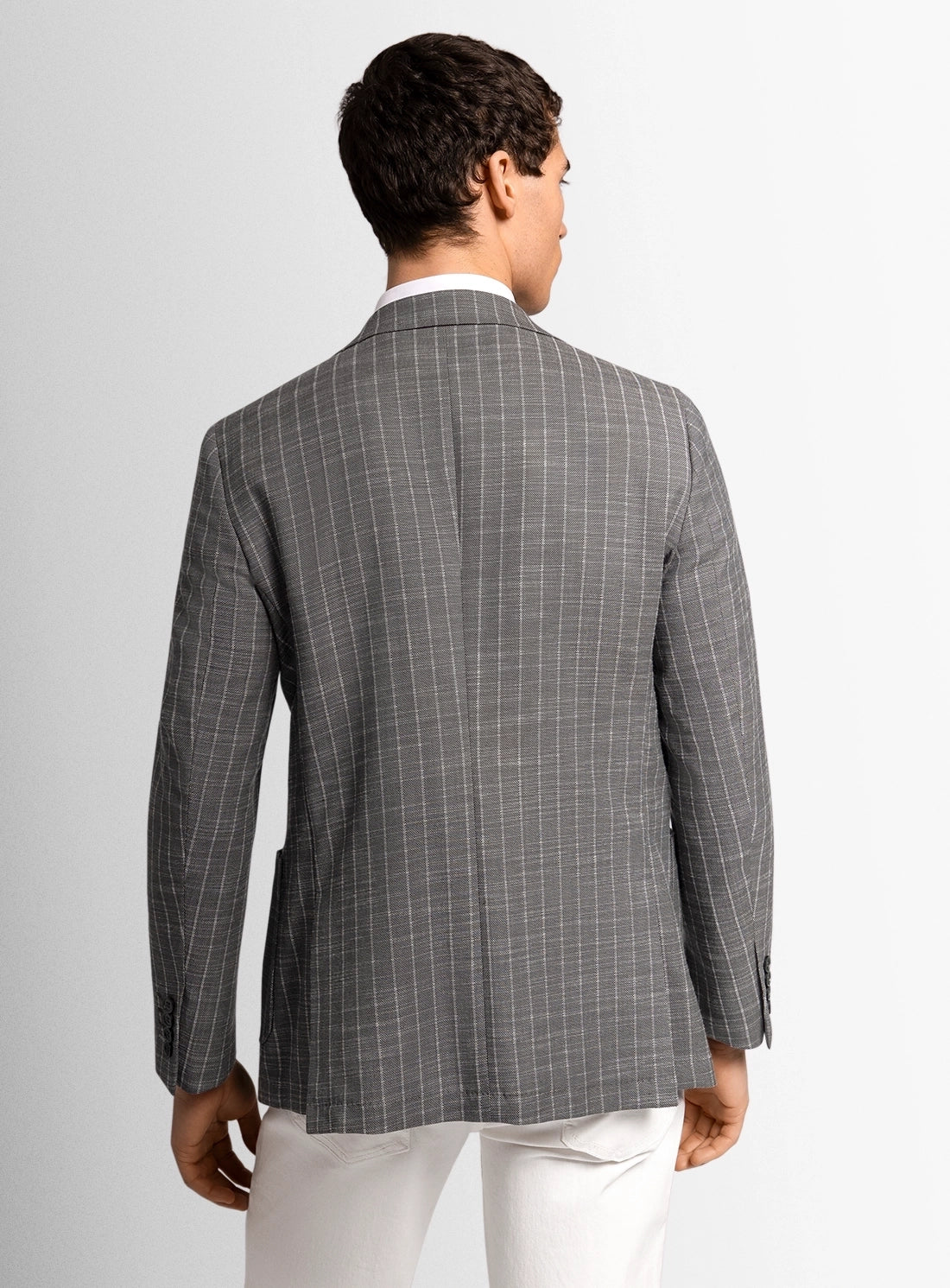 Man wearing a gray checkered blazer on a plain background
