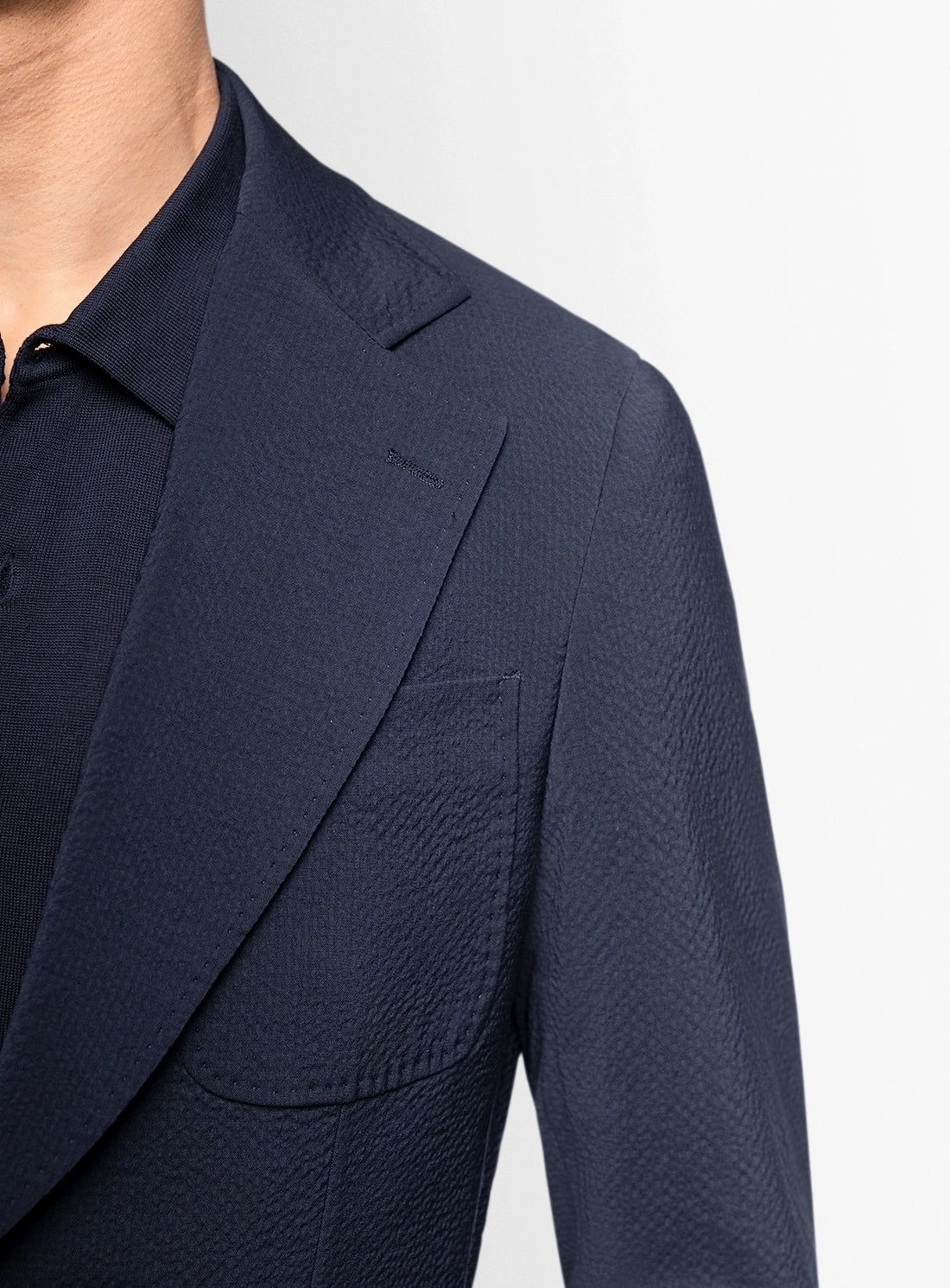 Navy blazer worn by a person on a light gray background