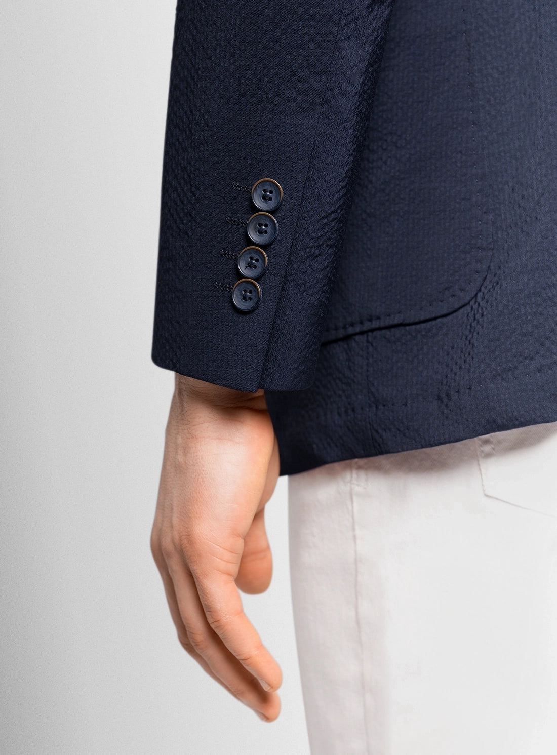 Navy blazer with three buttons on a light gray background
