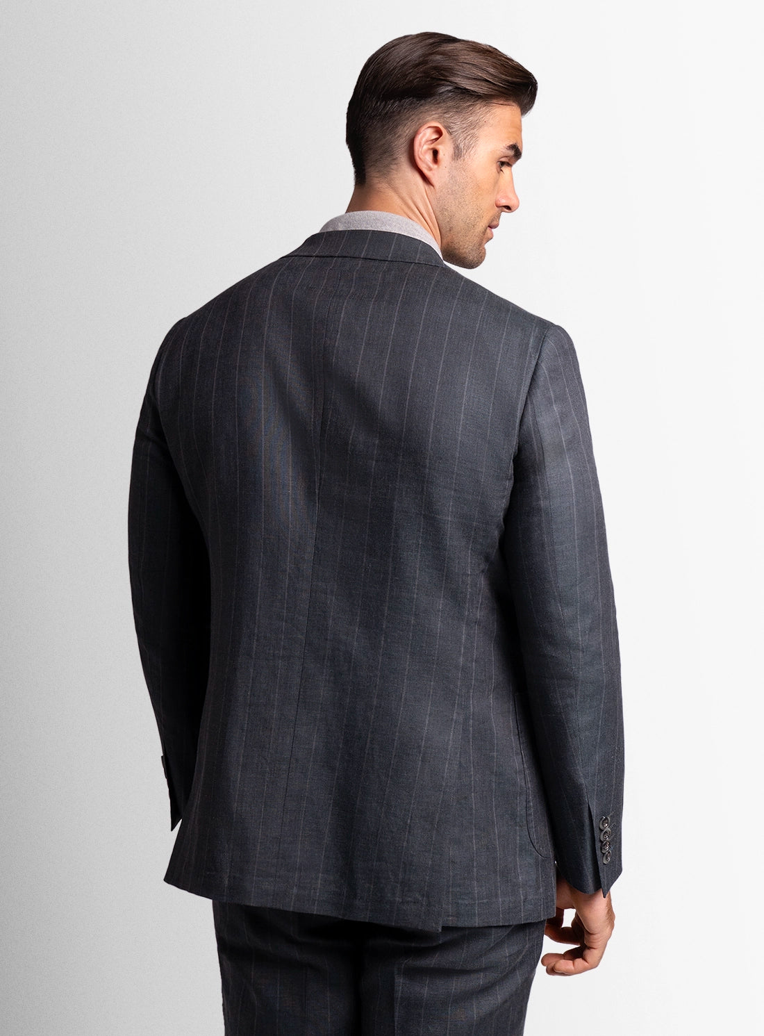 Man wearing a gray suit jacket on a plain background